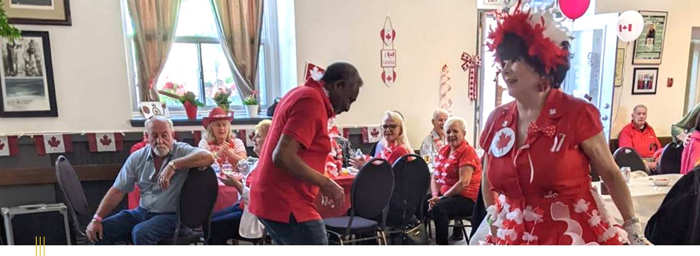 People celebrating July 1st at a Legion Branch, dancing and dressed in Canada Day fashion.