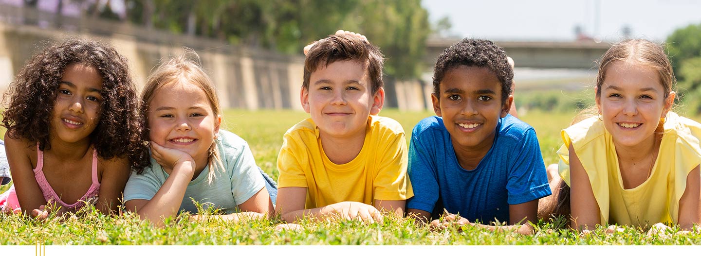 Group of smiling children laying on grass. 